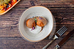 Close-up of two fried croquettes served with creamy dip
