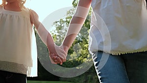 Close up of two girls walk together and hold hands