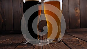 Close-up of two glasses of beer on a wooden background, dark beer and light beer
