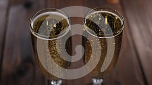 Close-up of two glasses of champagne with bubbles on a wooden background.