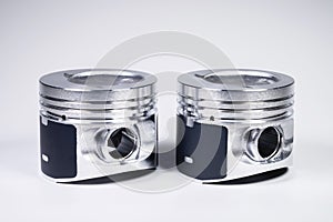 Close-up of two new internal combustion engine piston on a gray gradient background. The concept of new spare parts of