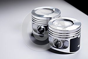 Close-up of two new internal combustion engine piston on a gray gradient background. The concept of new spare parts of