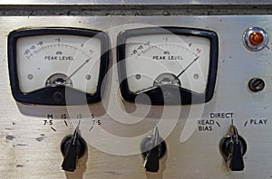 Close up of two old decibel meters on an old vintage reel to reel tape recorder with control knobs and switches