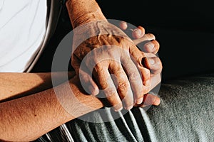 Close up of two old hands grabbing a young hand on cinematic tones