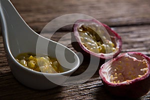 Two passion fruit and spoon with passion fruit pulp on wooden table