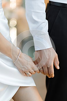 Close-up of two people holding hands showing wedding rings