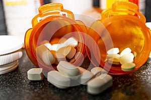 Close up of two pill bottles with white pills on dark counter