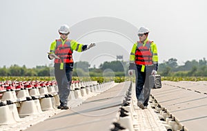 Close up two professional workers walk along footpath and discuss together in area of base of solar cell panels network