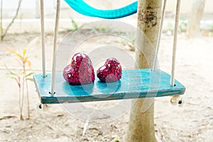 Close up of two red hearts on wooden table swing