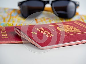 Close-up of two Russian passports lying on the map of the city. Black sunglasses in the background. The concept of travel and