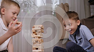 Close-up of two school-age boys playing an exciting wooden blocks board game.