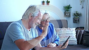 Close up of two seniors or old mature people doing a video call with friends or parents at home on the sofa in quarantine or lockd