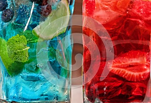 Close-up of two sweet bright cocktails with mint, lime, ice and strawberries as a background. Refreshing summer beverages for par