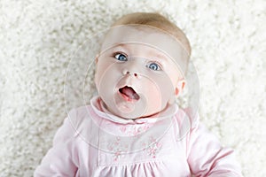 Close-up of a two or three months old baby girl with blue eyes. Newborn child, little adorable smiling and attentive