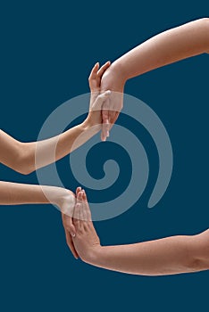 Close up of two women holding or measuring hands, touching each other palms isolated over blue background