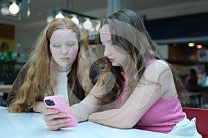 Close up of two young girls looking at smartphone playing mobile games, chatting in social media