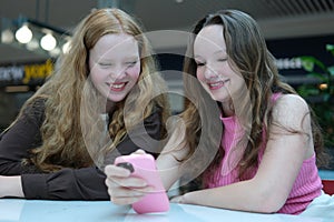 Close up of two young girls looking at smartphone playing mobile games, chatting in social media