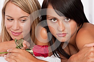 Close-up of two young naked woman with red rose photo