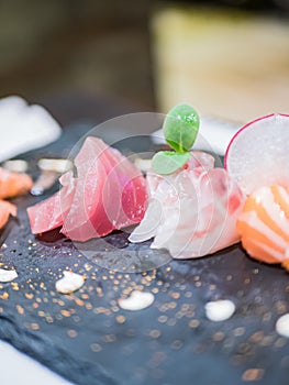 Close-up of a typical Japanese dish of sushimi with tuna salmon roll on a black background