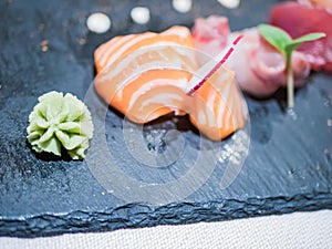 Close-up of a typical Japanese dish of sushimi with tuna salmon roll on a black background