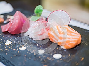 Close-up of a typical Japanese dish of sushimi with tuna salmon roll on a black background