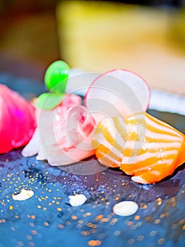 Close-up of a typical Japanese dish of sushimi with tuna salmon roll on a black background