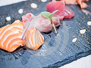 Close-up of a typical Japanese dish of sushimi with tuna salmon roll on a black background