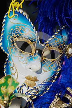 Close up of typical Venetian carnival masks with bright blue feathers.