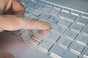 Close-up of typing male hands, grey silver keyboard button close up. Finger presses the enter button