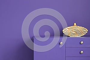 Close-up of an ultra violet wall and a matching cabinet with a g
