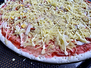 Close up of uncooked pizza prepared with cheese, corn, and crab stick for oven