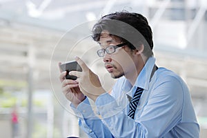 Close up of unemployed young Asian man looking mobile smart phone for find job. Unemployment concept.