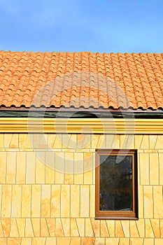 Close up unfinished roof. Roof house with tiled roof on blue sky. marble tile on the wall in a new window. Unfinished roof.