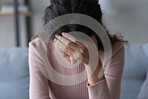 Close up unhappy depressed young woman touching forehead