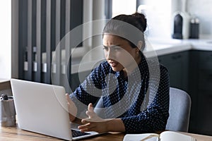 Close up unhappy Indian woman looking at laptop screen