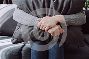 Close up of unhappy lonely depressed young female, upset anxiety woman sitting on couch and hiding face on grey pillow, depression