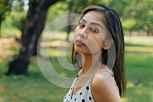 Close-up of unhappy Southeast Asian woman with tears looking at camera in outdoor park. Portrait of depressed and