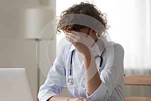 Close up unhappy stressed woman doctor covering face with hand