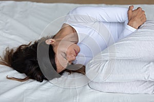 Close up unhappy woman suffering from bellyache, lying on bed