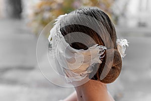 Close-up of unique white feather headband tiara wrapped around a ballerina girls hair bun