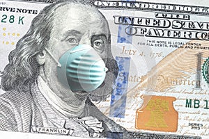 Close up of United States paper currency one hundred dollar bill with Benjamin Franklin wearing blue face mask due to COVID-19