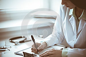 Close up of  unknown female doctor sitting  at the table near the window in hospital