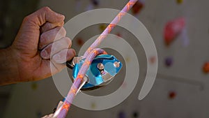 CLOSE UP: Unrecognizable belayer helps a climber descend after climbing a wall