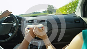 CLOSE UP: Unrecognizable couple toasts in the car with disposable coffee cups