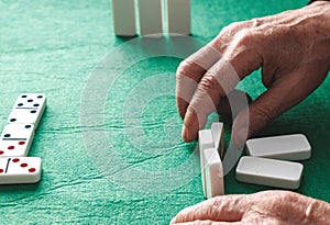 Close-up of an unrecognizable elderly person with wrinkles and veins playing a game of dominoes