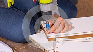 CLOSE UP: Unrecognizable female assembles her furniture with a cordless drill.