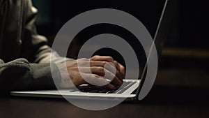 Close-up of unrecognizable hacker man stretching hands and starting to typing on laptop keyboard.