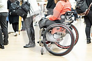 Close up of unrecognizable hanicapped woman on a wheelchair queuing in line to perform everyday tasks.
