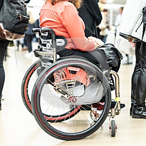 Close up of unrecognizable hanicapped woman on a wheelchair queuing in line to perform everyday tasks. photo