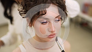 Close-up of unrecognizable makeup artist making face make up putting powder using brush, hairdresser making hair-do for